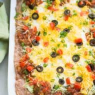 Everyone loves this easy 7-layer bean dip that has layers of flavored refried beans, guacamole, sour cream, salsa, cheese, olives and green onion. | tastesbetterfromscratch.com