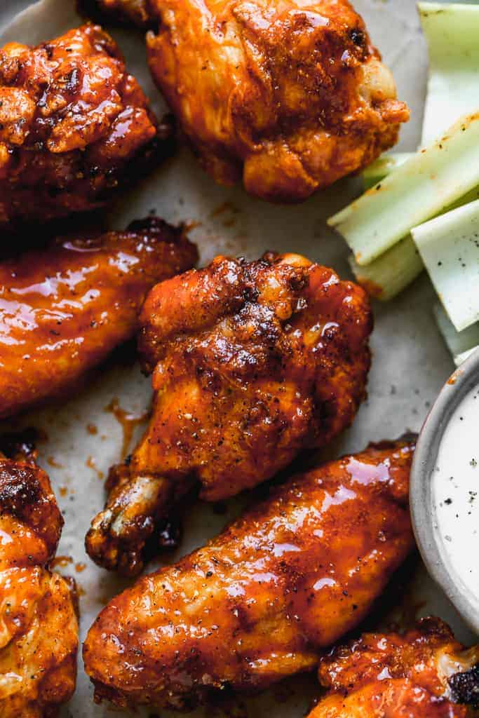 Close-up of a baked chicken wing with hot sauce on it.