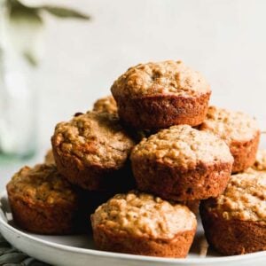 Banana Oat Muffins stacked on a plate.