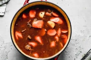 Beef stew ingredients added to a large pot.