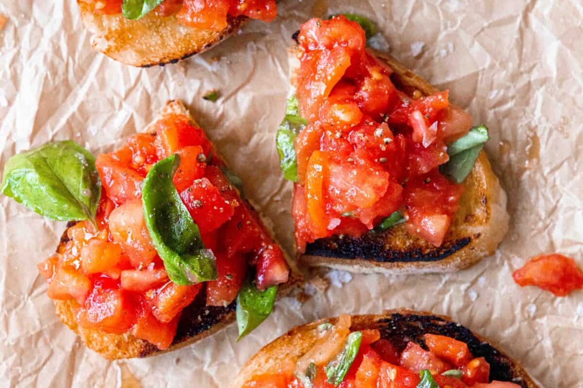 Bruschetta toast cut in half, on a piece of parchment paper.