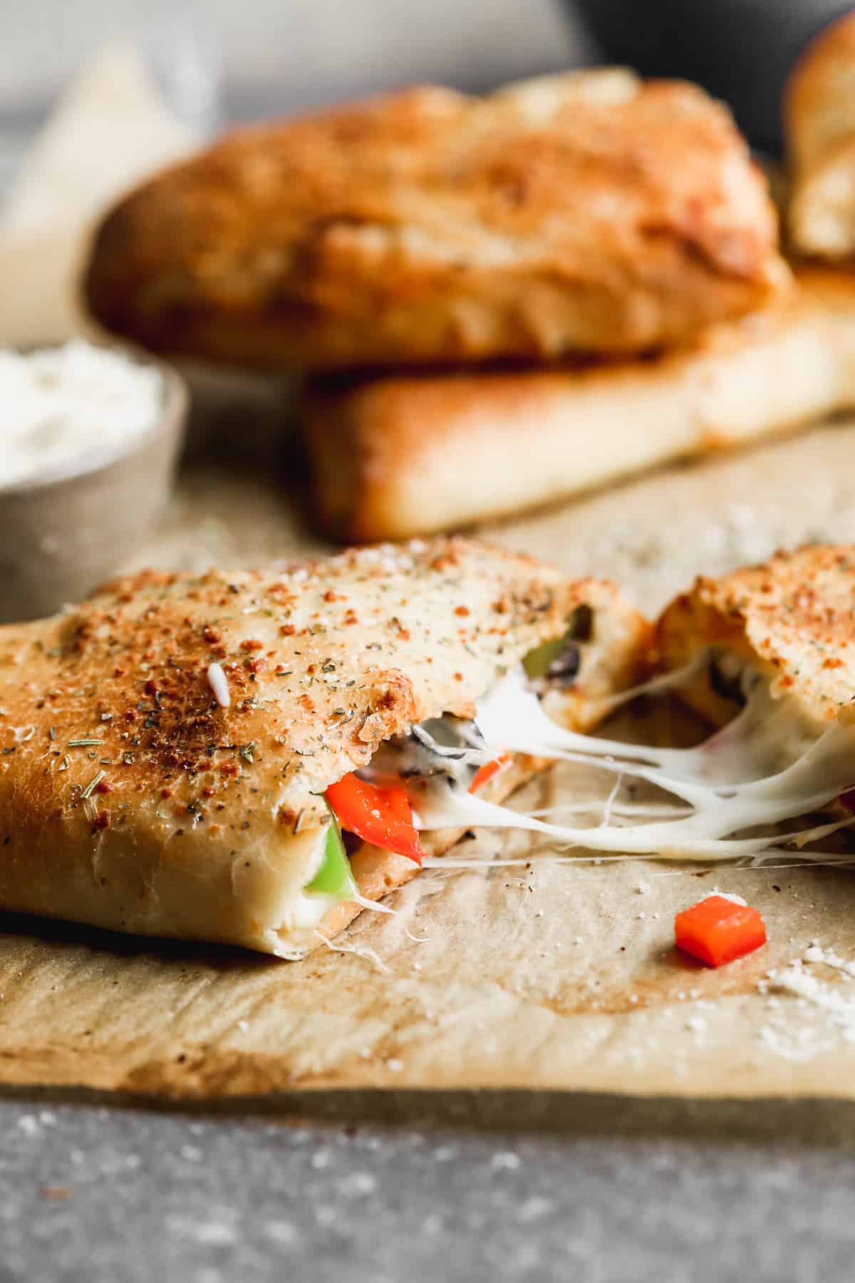 A calzone being pulled apart to show the bell peppers and cheese fillings inside.