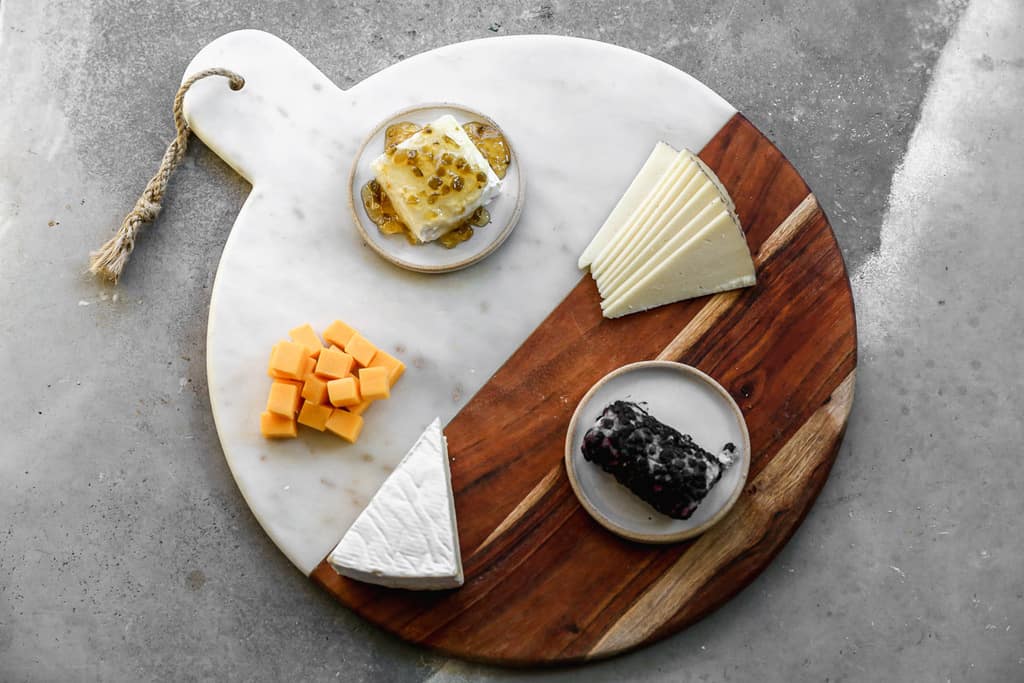 Five types of cheese arranged on a charcuterie board.