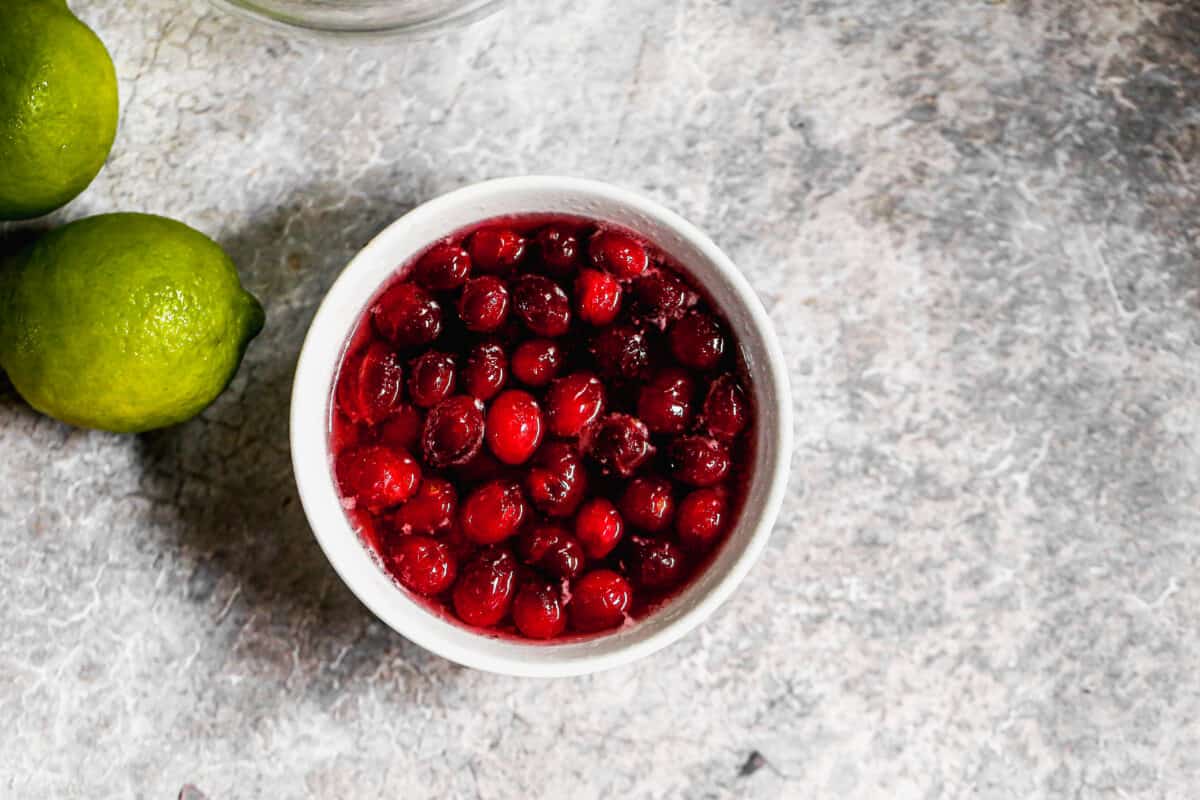 A bowl of cranberries, sugar, and water after being cooked with the cranberries popped open.