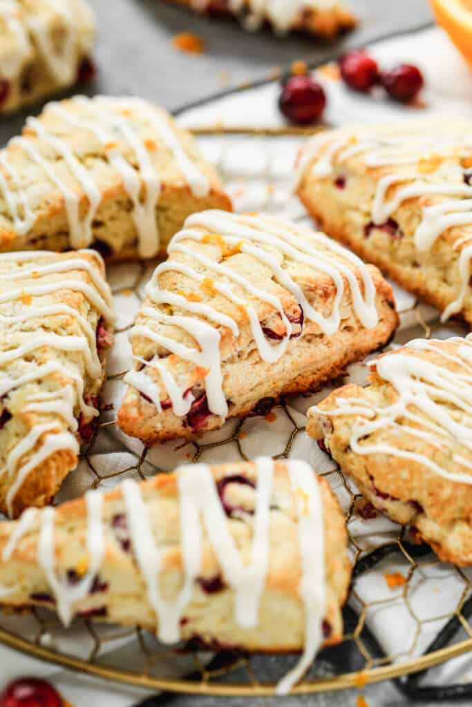 Homemade cranberry orange scones arranged on a decorative wire rack.