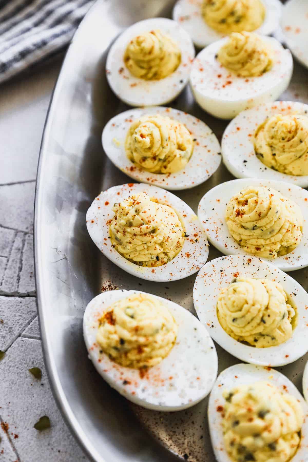 The best Deviled Eggs recipe on a silver platter, sprinkled with paprika and ready to enjoy.