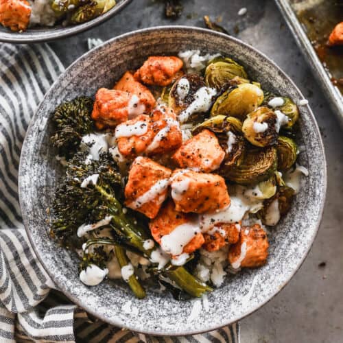 A homemade Hot Honey Salmon Bowl with salmon, broccolini, and brussels sprouts on a bed of rice.