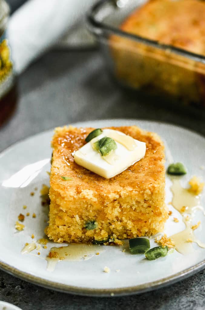 A slice of jalapeño cornbread on a plate, with a little butter on top.