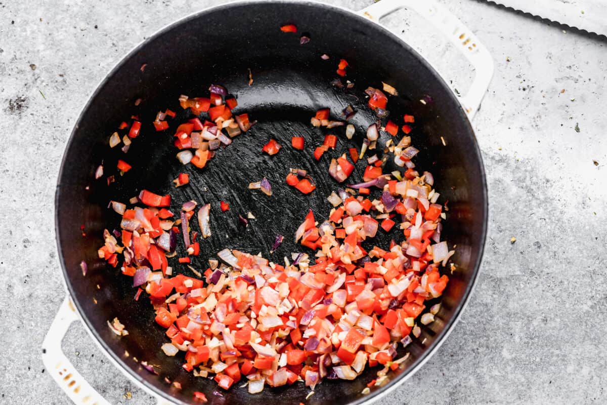 Onion and bell pepper being sautéed with ginger, garlic, and spices.