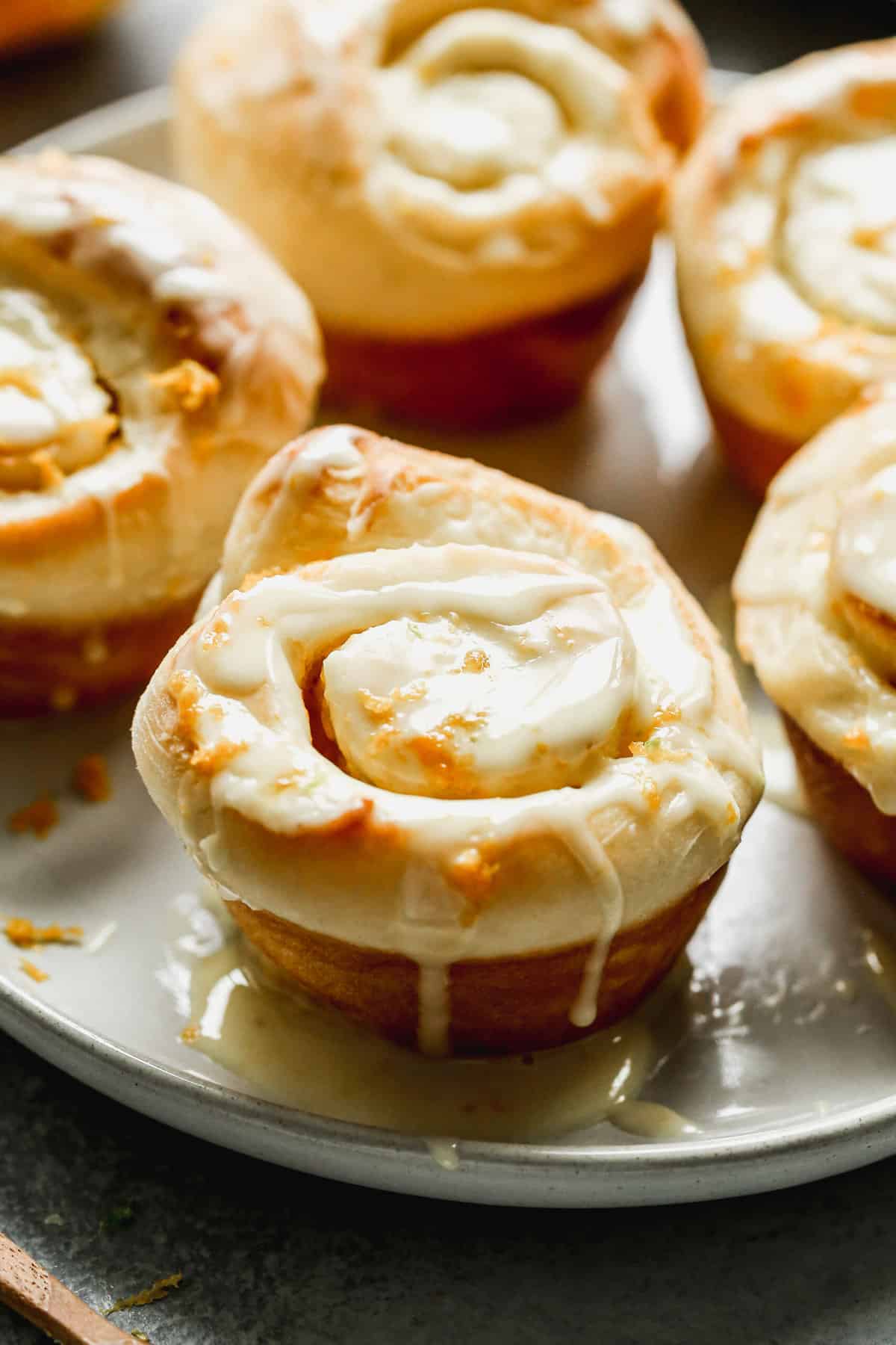 Homemade Orange Rolls on a plate, topped with orange glaze and orange zest.