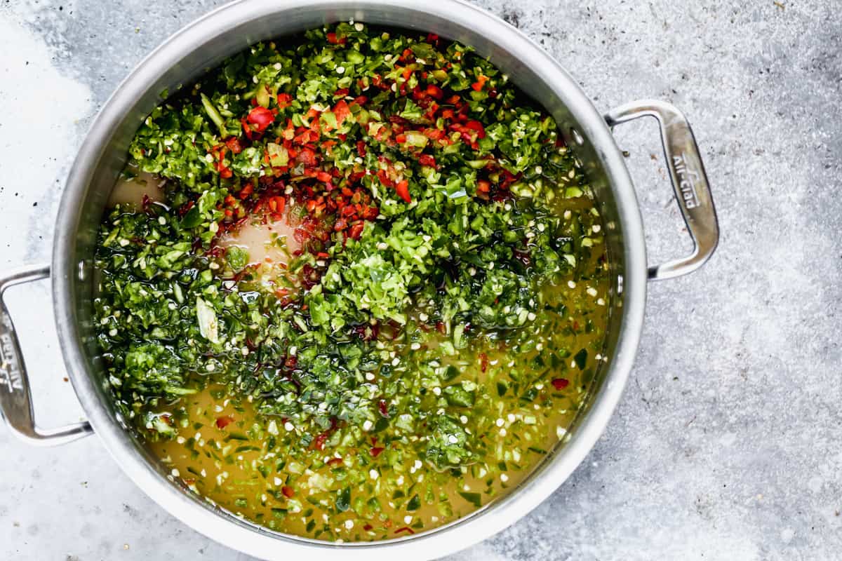 A stainless steel pan filled with diced peppers, sugar, vinegar, lime juice, and salt to make easy pepper jelly.