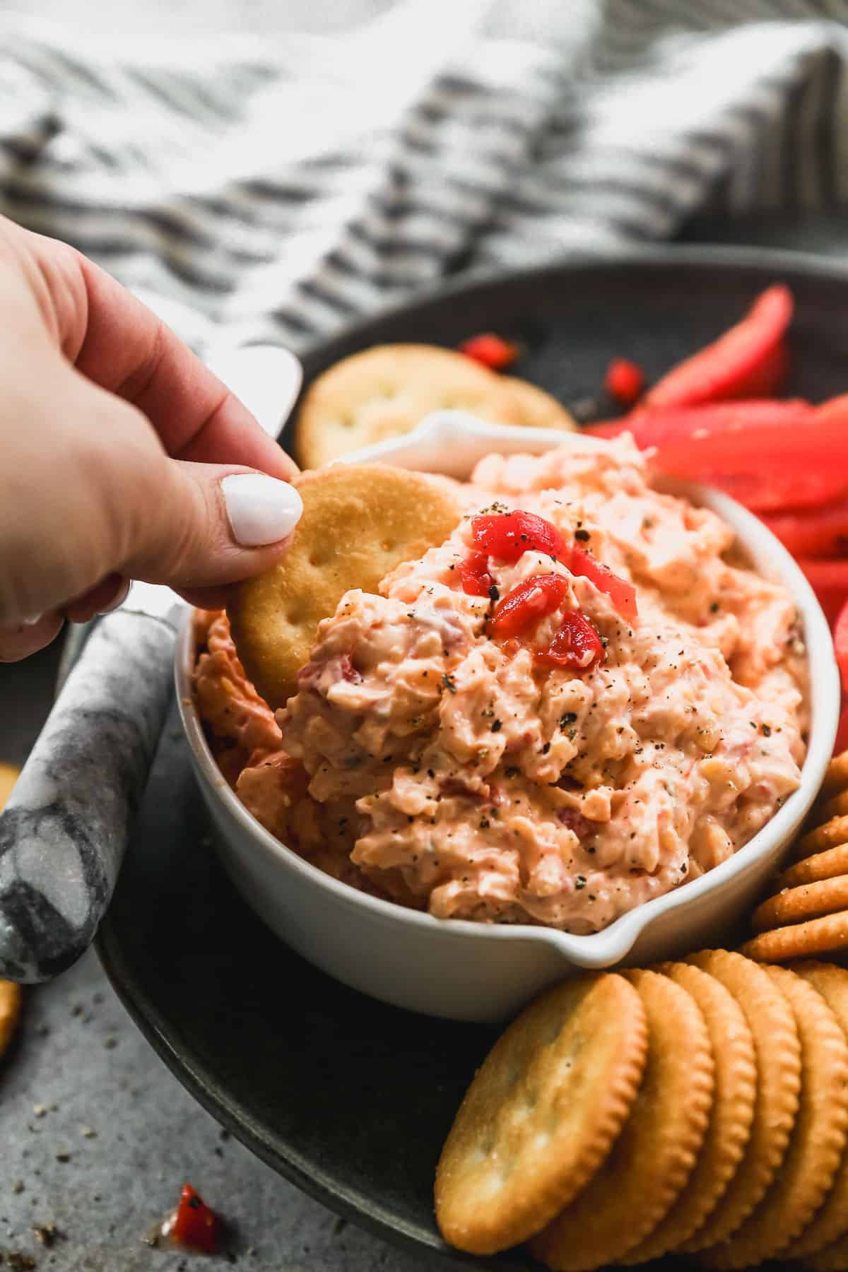 An image showing a ritz cracker being dipped in an old fashioned pimento cheese recipe.