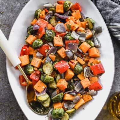 A serving dish filled with the best Roasted Vegetables: a mix of butternut squash, red onion, red bell pepper, and brussels sprouts.