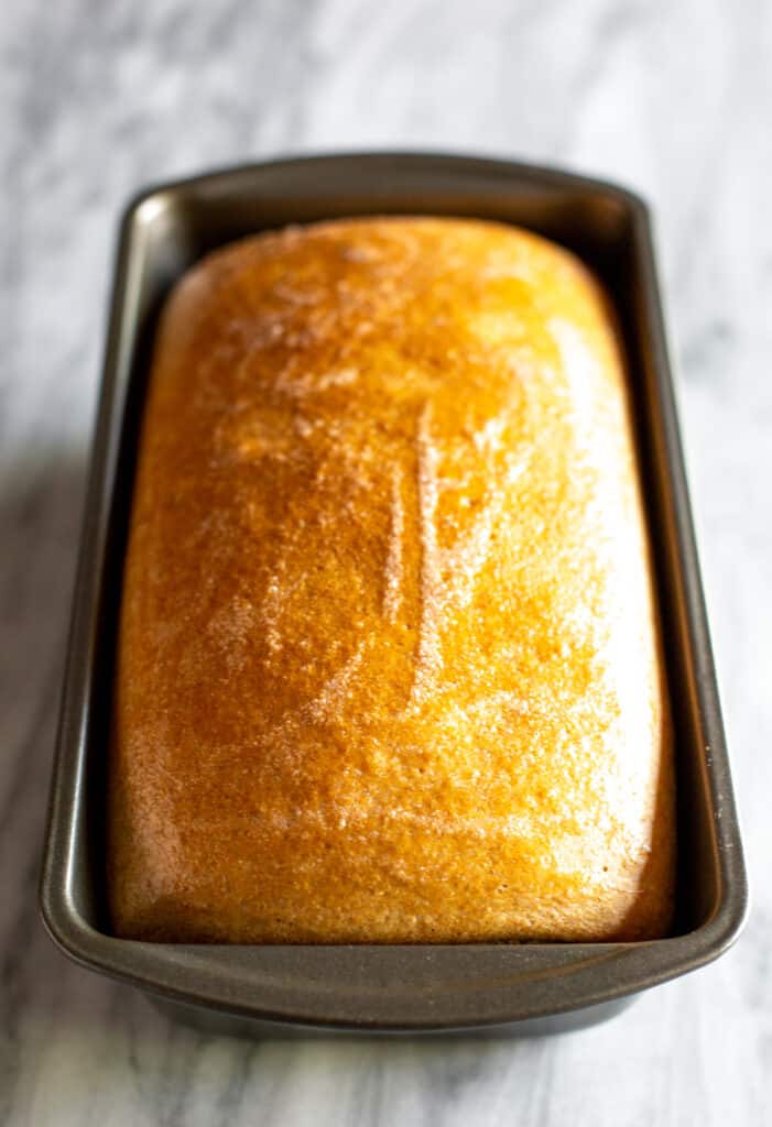 A loaf pan with baked whole wheat bread in it.