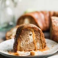 A slice of Apple Bundt Cake on a plate with caramel sauce on top.