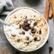 Arroz con Leche receta in a bowl with a dusting of cinnamon sugar and topped with some raisins.