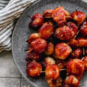 A plate of water chestnuts wrapped in bacon with a delicious glaze, ready to enjoy with toothpicks.