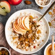 A bowl of a Swiss Bircher Muesli recipe packed with grated apple, golden raisins, almonds, honey, and a sprinkle of cinnamon.