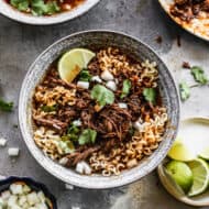 A bowl of Birria Ramen topped with cilantro and a lime wedge, ready to enjoy.