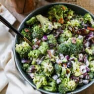 The best Broccoli Salad with bacon, craisins, and onion in a large bowl with a serving spoon.