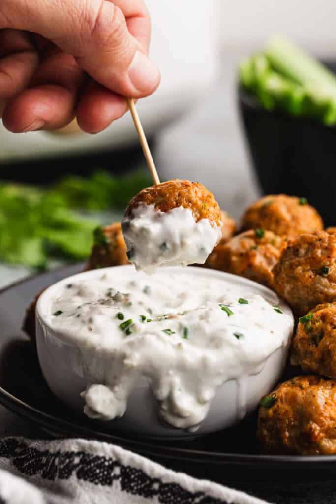 A chicken buffalo meatball being dipped in ranch sauce.