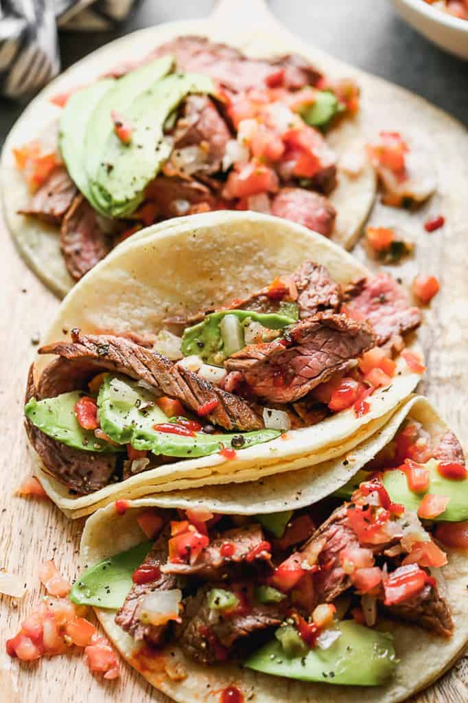 Three Carne Asada Tacos served in corn tortillas topped with pico de gallo and avocado.