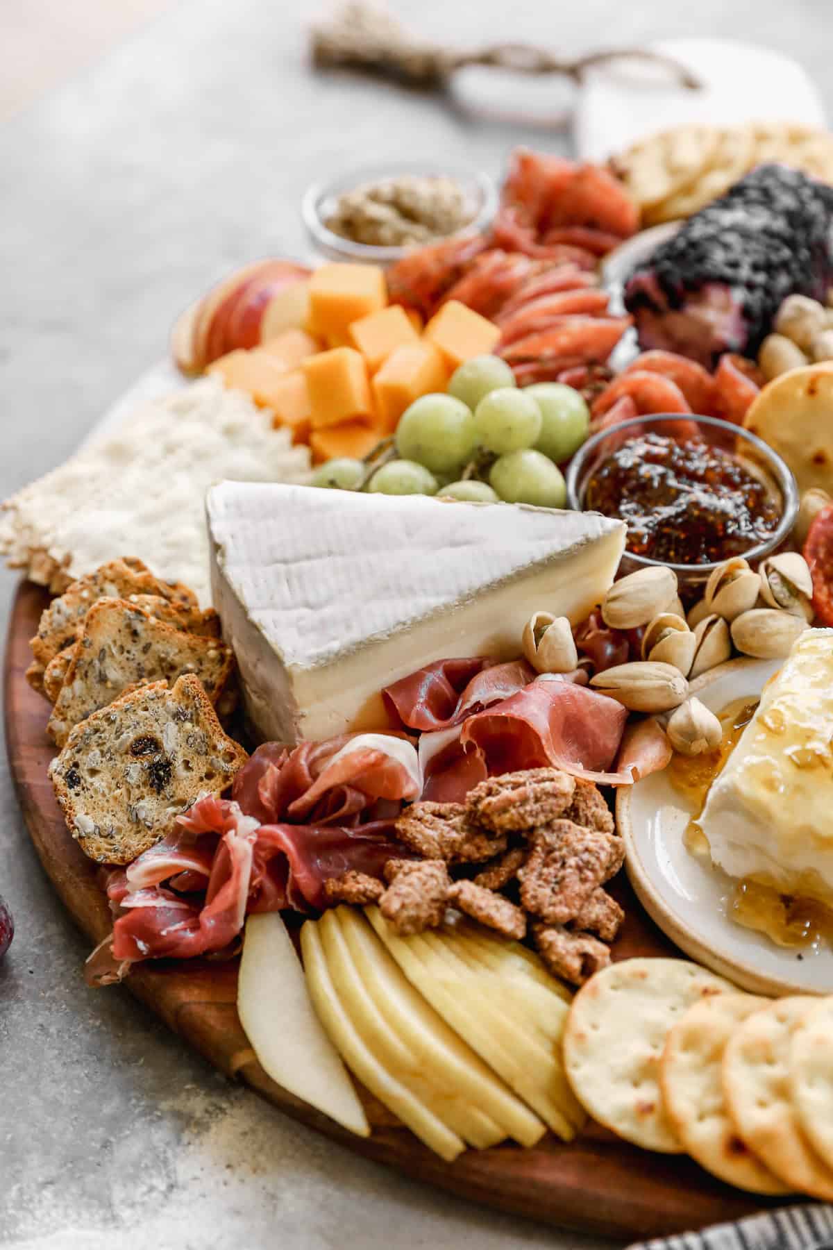 A meat and cheese charcuterie board with different cheeses, meats, fruit, and crackers. 