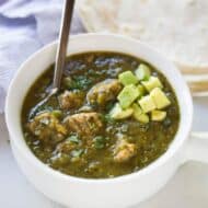 Authentic chile verde pork garnished with fresh avocado and served with a side of flour tortillas. - tastesbetterfromscratch.com