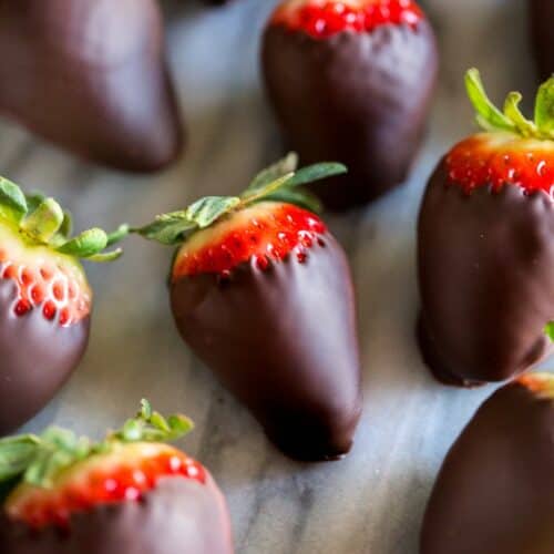 Chocolate covered strawberries on a white marble board.