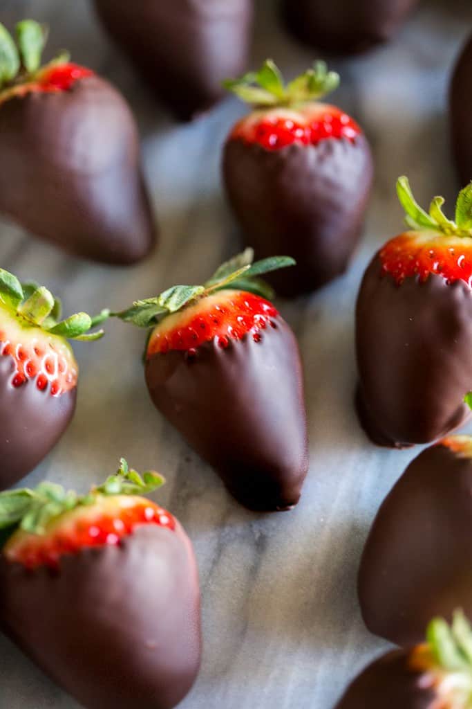 Chocolate covered strawberries on a white marble board.