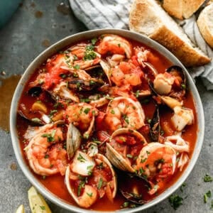 A bowl of the best Cioppino recipe with shellfish, white fish, clams, mussels, and served with crusty bread.