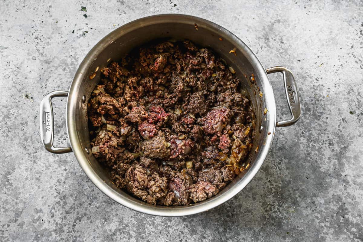 Beef and sausage browned with onion in a large pot. 