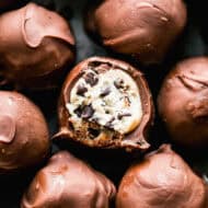 Chocolate Chip Cookie Dough Truffles in a pile with a bite out of the center one to show the cookie dough center.