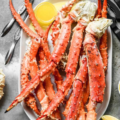 King Crab Legs heated until hot then served on a tray with a cup of melted butter.