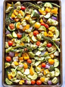 A sheet pan with pesto chicken and chopped vegetables.