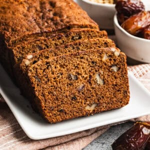 An old fashioned date nut bread recipe on a white platter with a few slices cut to show the dates and walnut chunks.