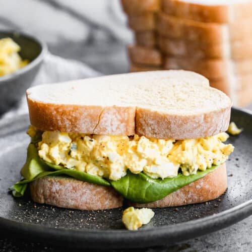 The best Egg Salad Sandwich sitting on a black plate, ready to enjoy.