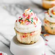 A homemade funfetti cupcake on a plate, with buttercream frosting and sprinkles on top.