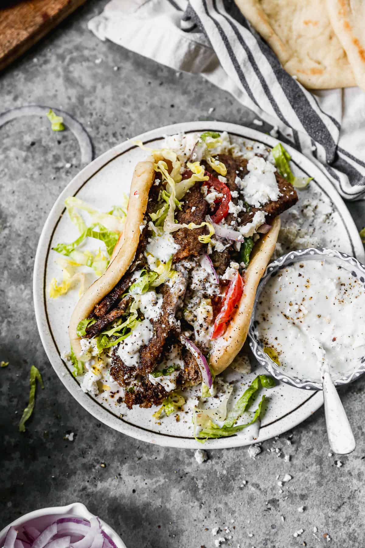 A Greek gyro in a pita and topped with veggies, ready to enjoy.