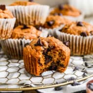 Healthy Pumpkin Chocolate Chip Muffins on a platter with a bite taken out of the front one.