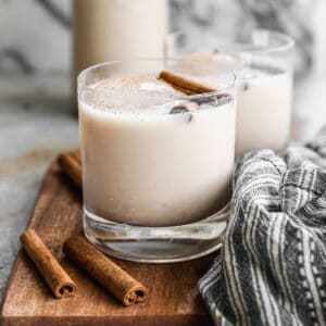 Horchata in a glass of ice topped with a cinnamon stick.