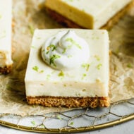 Easy key lime pie bars cut into squares and topped with whipped cream and fresh lime zest.