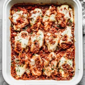 A pan of easy Stuffed Shells with a ricotta and meat sauce stuffed inside each shell then the meat sauce poured on top.