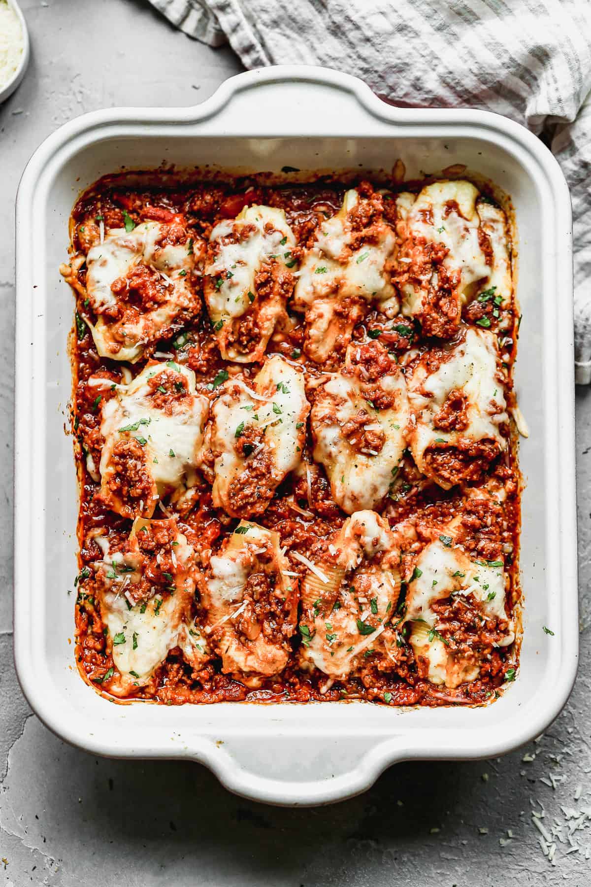 A pan of easy Stuffed Shells with a ricotta and meat sauce stuffed inside each shell then the meat sauce poured on top.