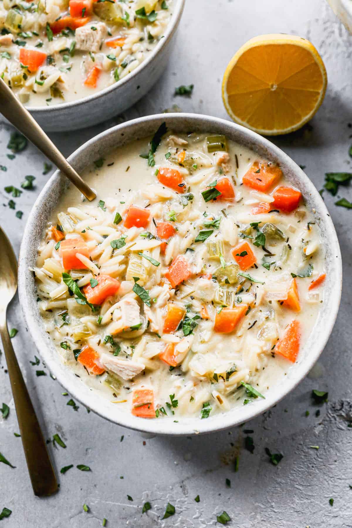 A creamy Lemon Chicken Orzo Soup recipe packed with chicken and vegetables in a bowl ready to enjoy. 