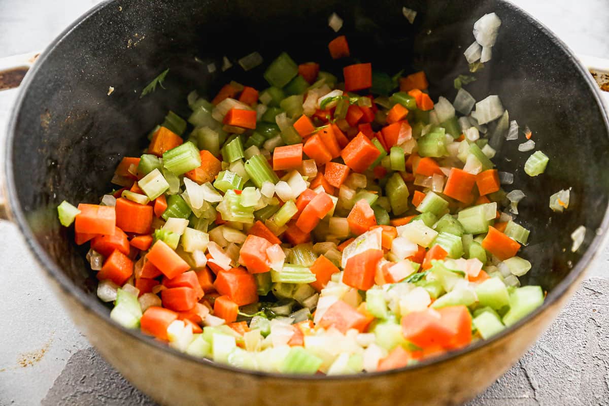 Chopped carrots, celery, and onion in a pot being sautéed. 