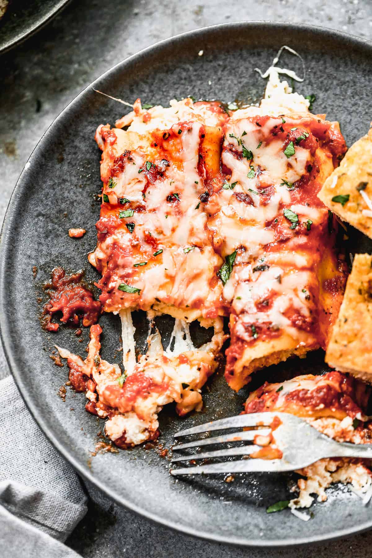 A plate of homemade Manicotti with a fork cutting a bite. 