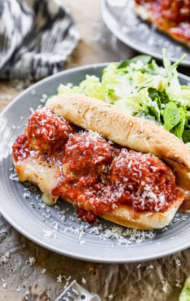 A homemade Meatball Sub sandwich recipe with a toasted sub with melted cheese, topped with three meatballs, marinara sauce, and a sprinkle of parmesan cheese.