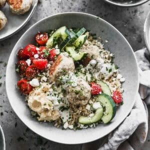 An easy Mediterranean Meatball Bowl served over rice, with turkey meatballs, and topped with fresh veggies and a homemade tzatziki sauce.