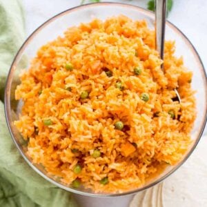 Mexican Rice with peas and carrots, served in a large bowl, with a spoon.